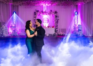A couple dancing on a misty floor with dramatic purple and blue lighting effects.