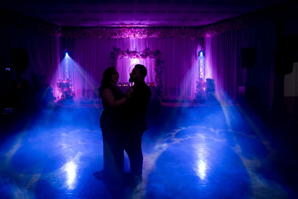 A silhouetted couple embracing on a dance floor with dramatic purple and blue lighting effects.