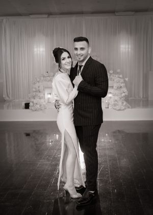 Elegant couple poses together in formal attire against white backdrop.