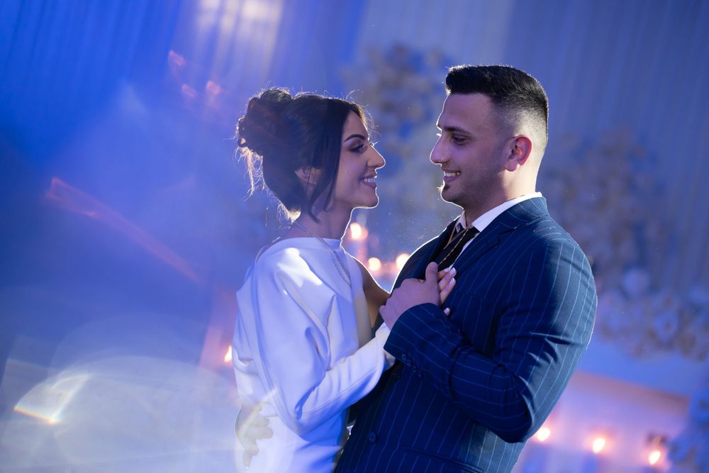 Couple shares intimate dance moment under blue atmospheric lighting.