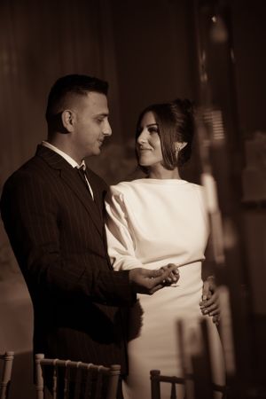 A couple shares an intimate moment during their wedding reception in sepia tones.