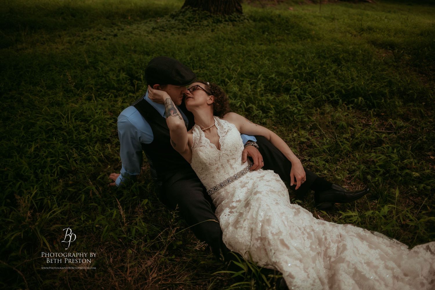 Romantic moment captured during outdoor wedding photoshoot in a lush green setting.