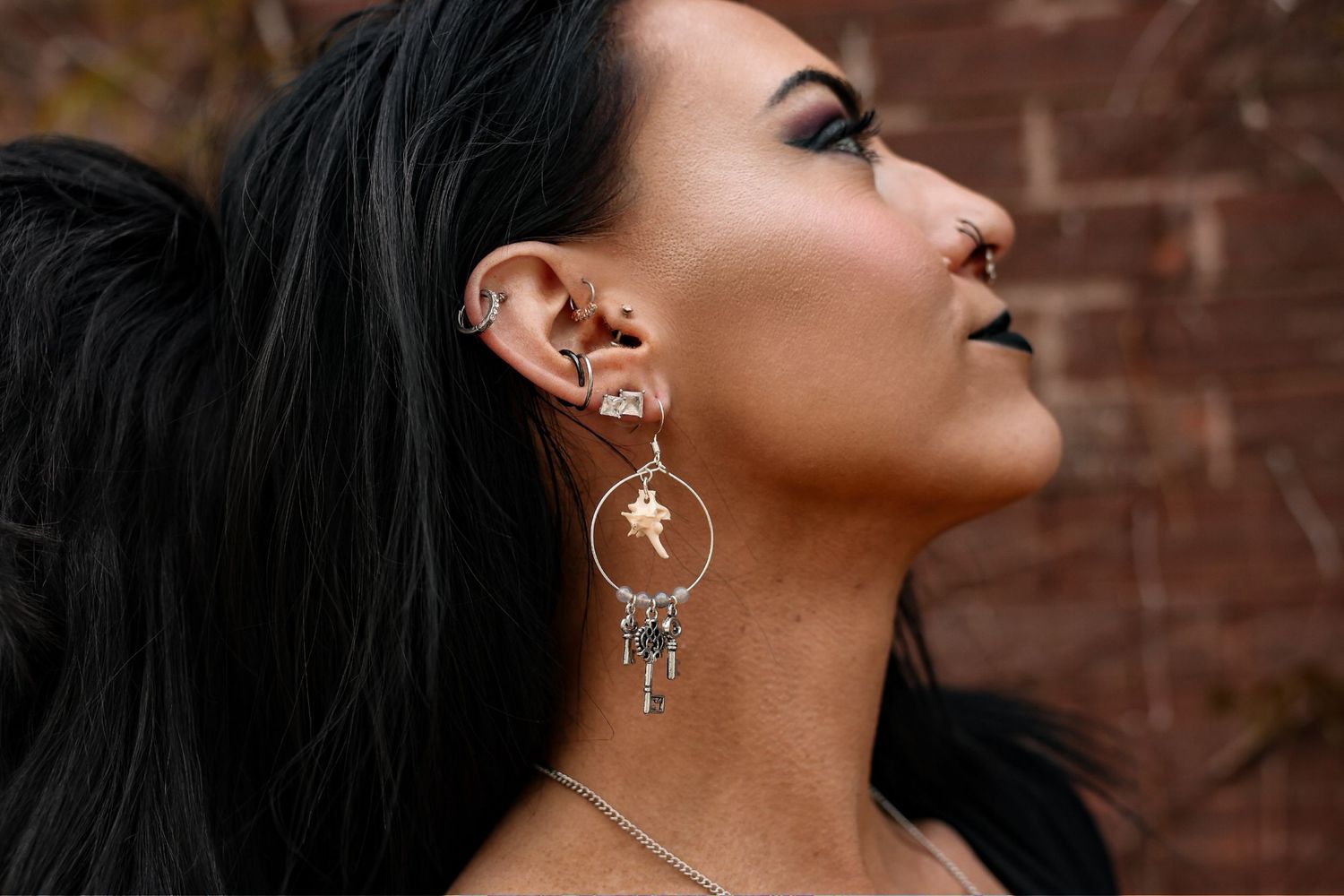 Side profile shot showing gothic-style earring and jewelry details.