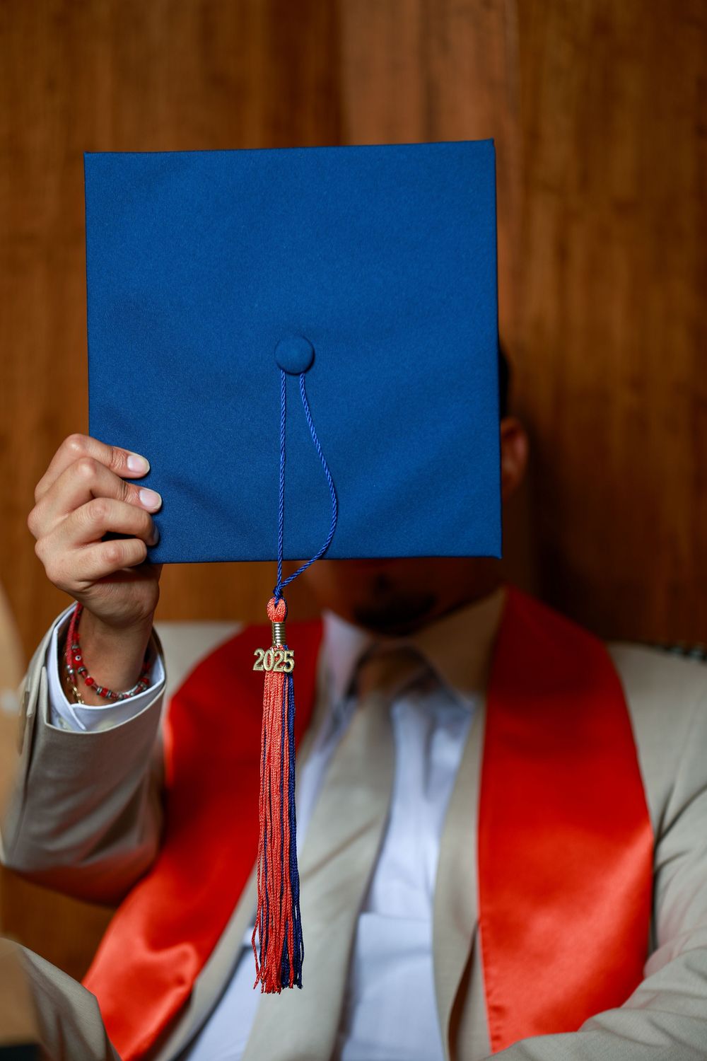 Blue graduation cap with red tassel shown in different angles against wooden background.