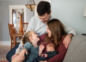 Family sharing intimate moment on couch with newborn baby.