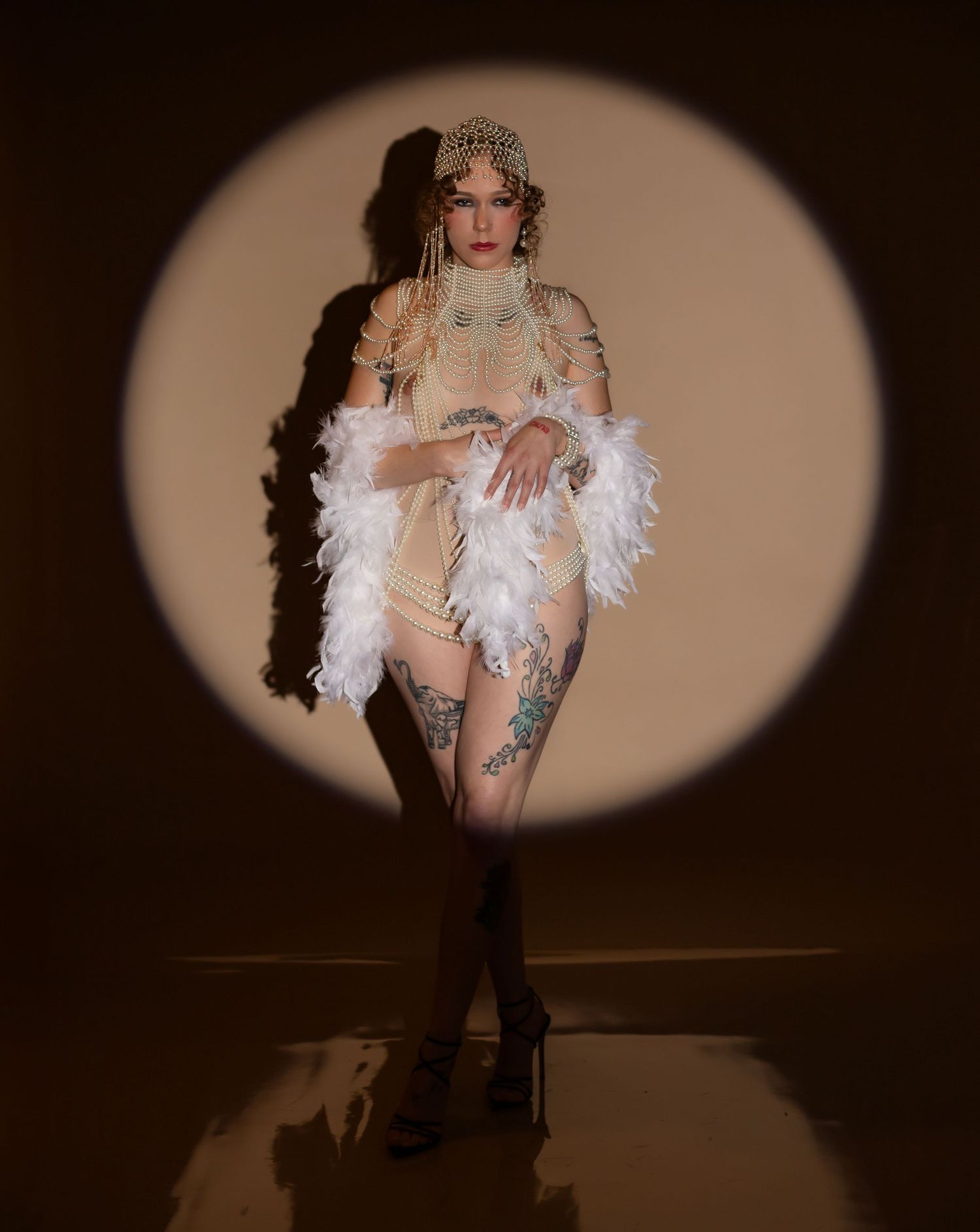 Artistic boudoir photo series showing figure in white feathers and lingerie against dark background with dramatic lighting in Akron Ohio.
