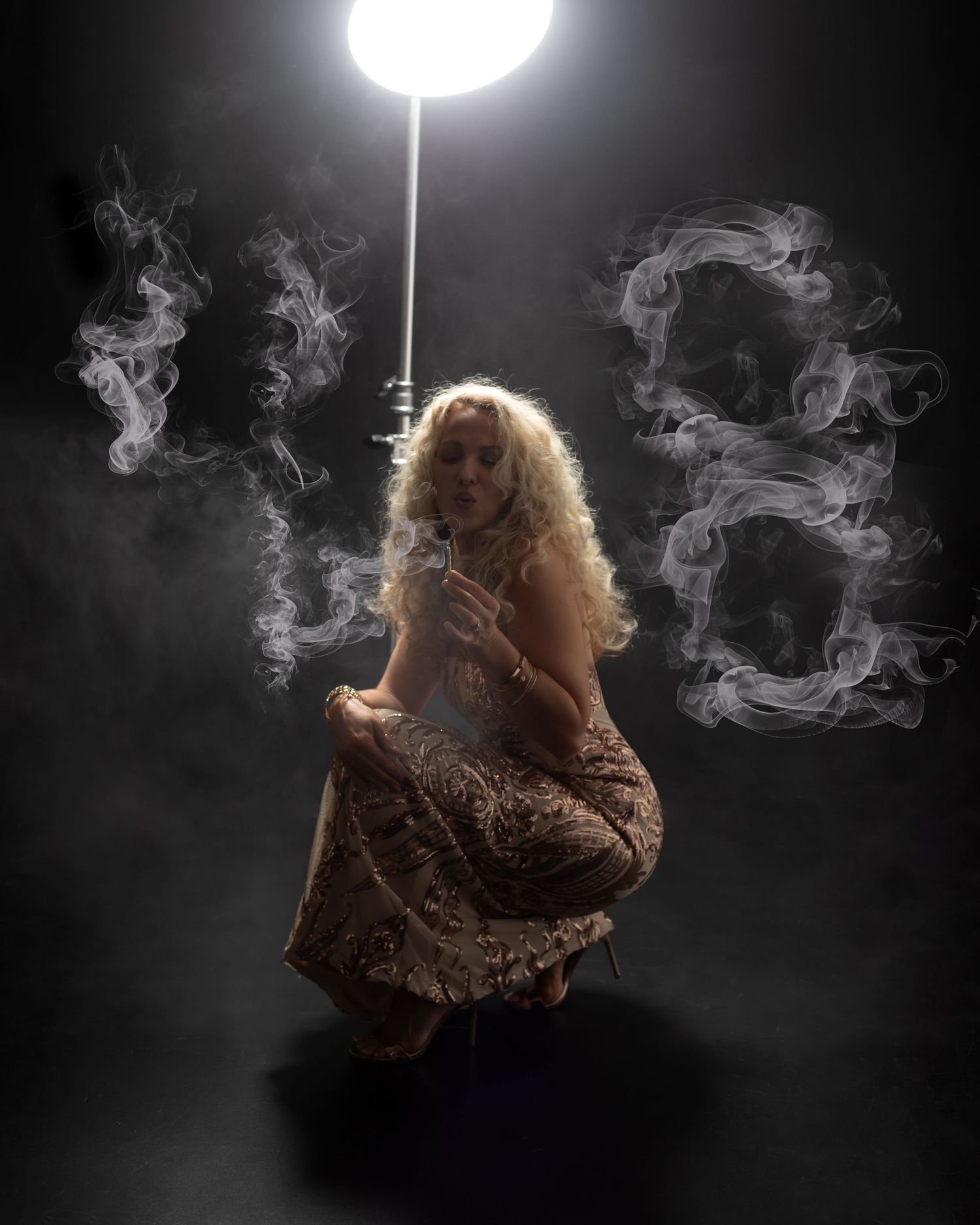 Artistic portrait in dark setting with swirling smoke effects and single overhead light illuminating figure in flowing dress in Akron Ohio.
