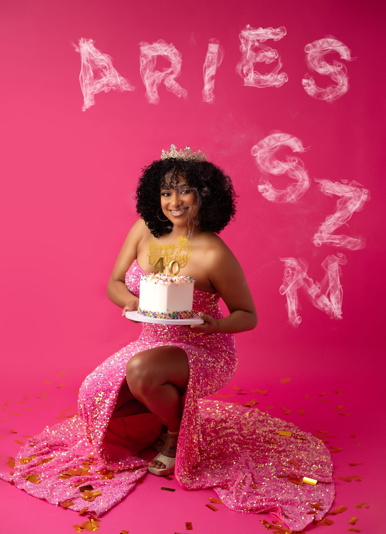 A women in a pink sparkly tulle dress and crown with a pink backdrop with scattered gold confetti for a fashion Birthday shoot in Akron Ohio
