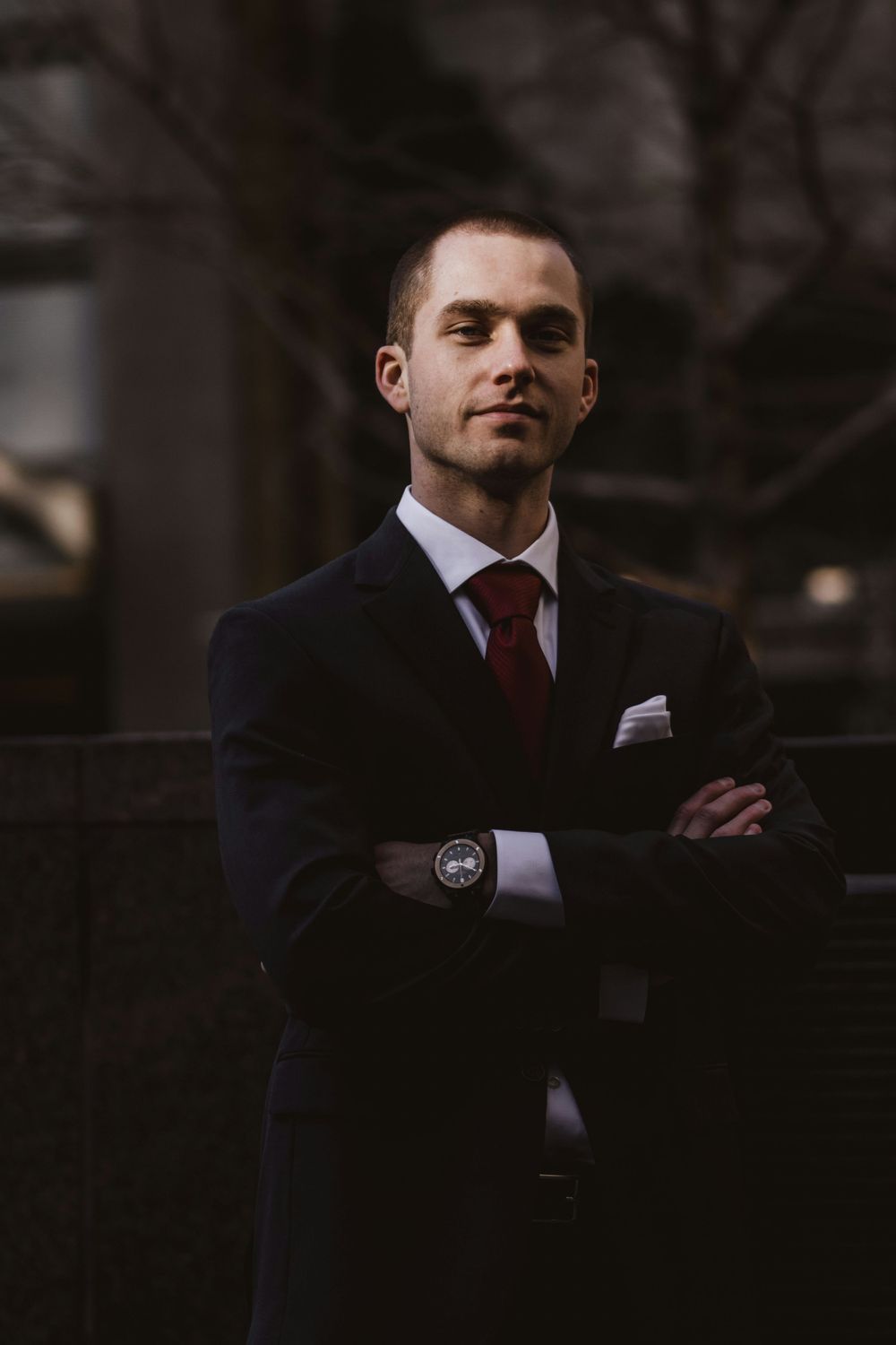 Moody portrait of a professional in a dark suit and tie at dusk.