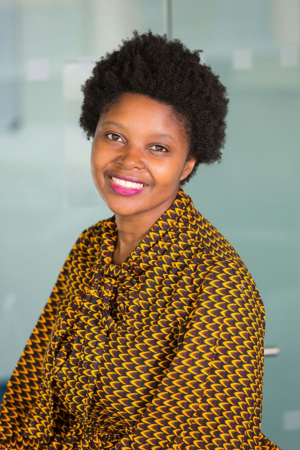 Professional portrait of someone wearing a vibrant yellow and black patterned top.