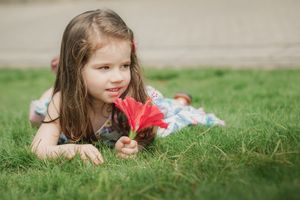 Someone lays on the grass in a series of images wearing a red sweater.