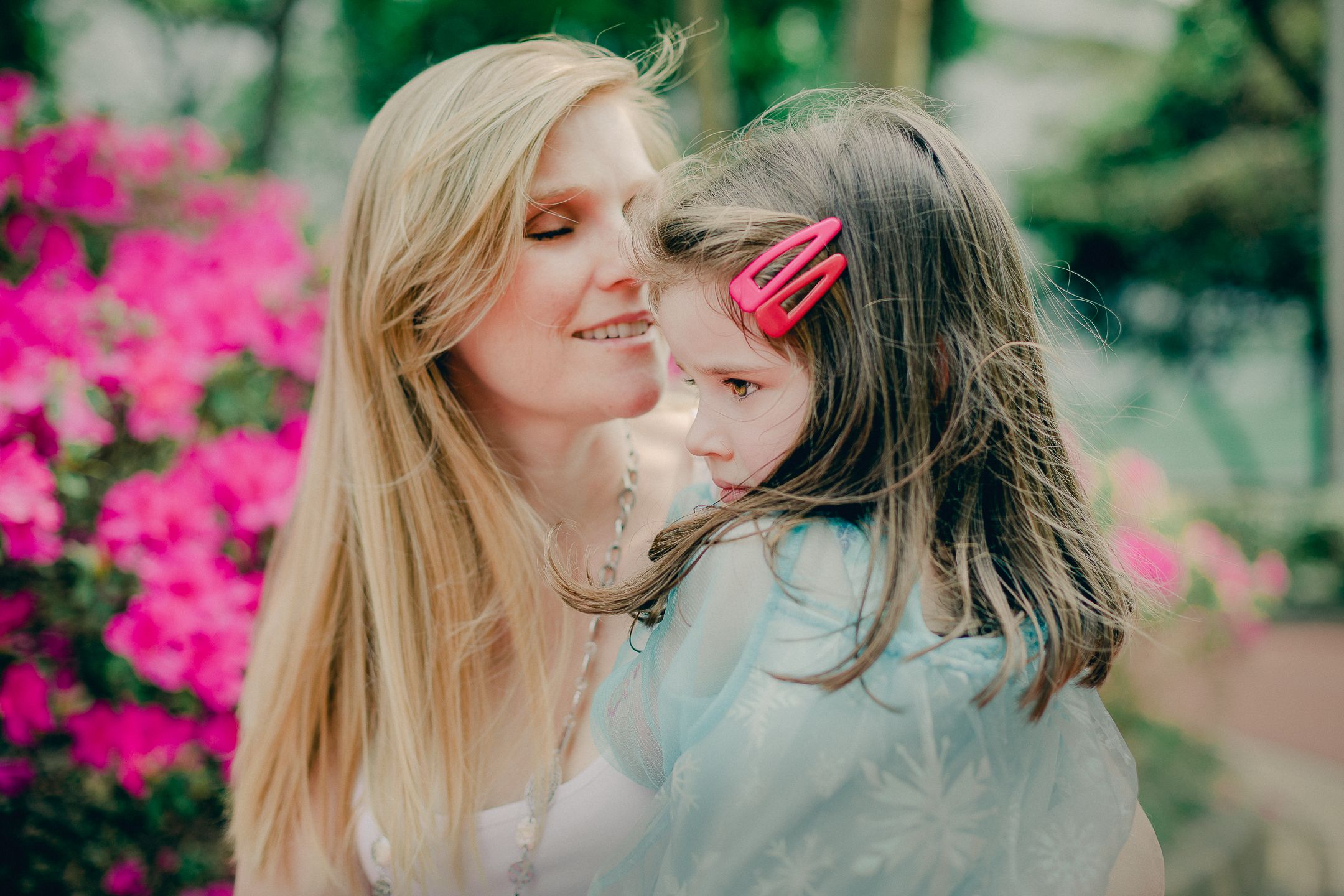 A series of romantic couple portraits set against vibrant pink flowers and greenery in an outdoor garden setting.