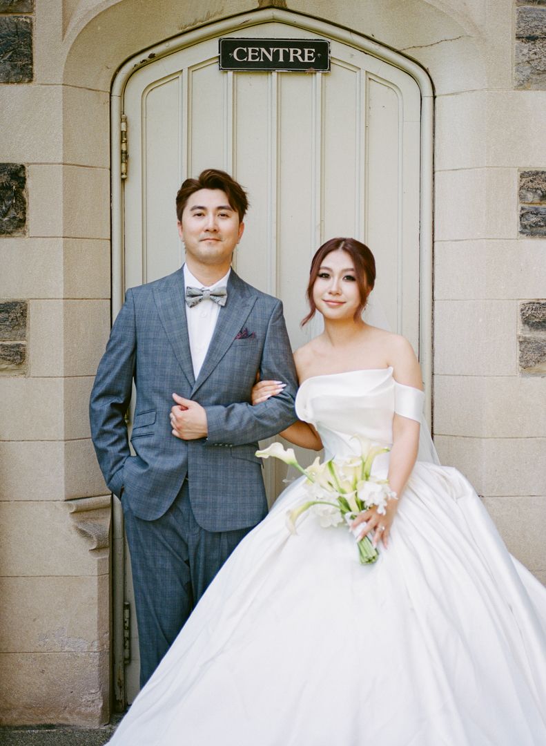 Bride and groom pose in front of door marked "Centre" during Knox College wedding photo shoot.