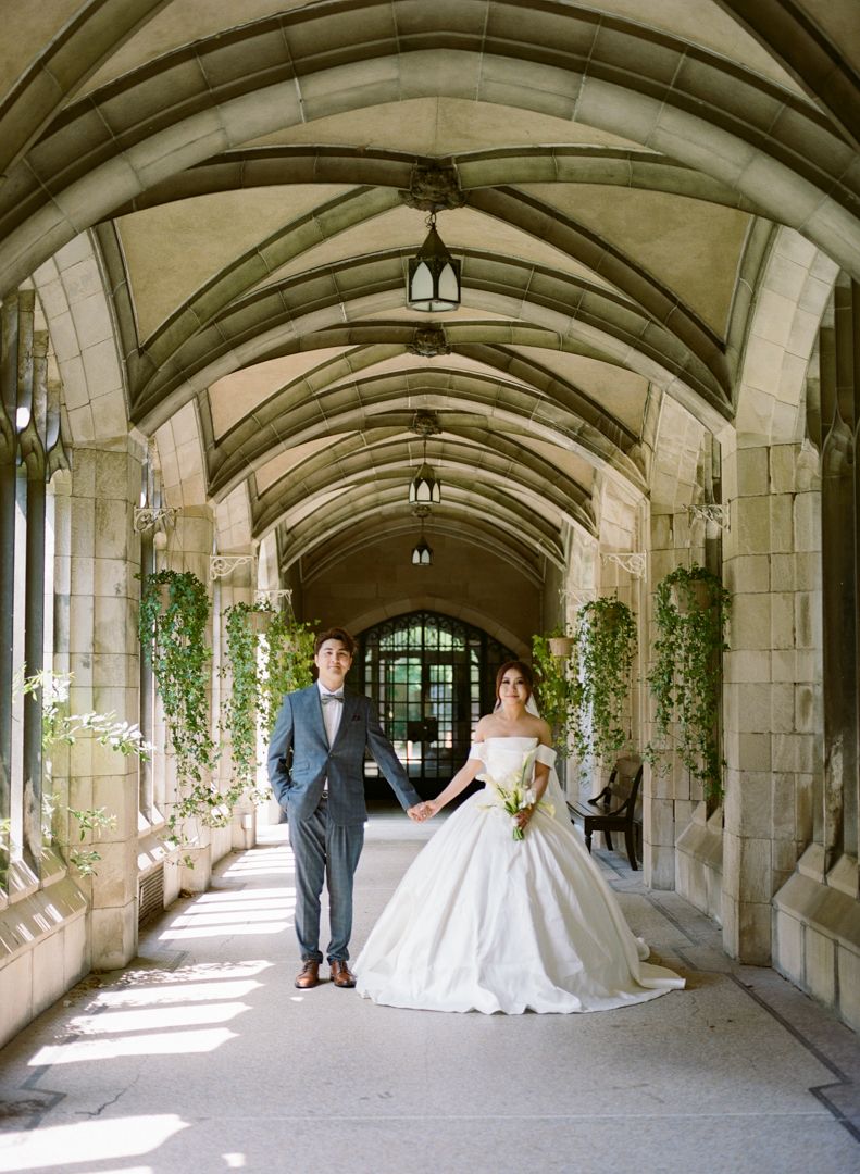 Bride and groom holding hands under arched hallway at Knox College wedding photo session.