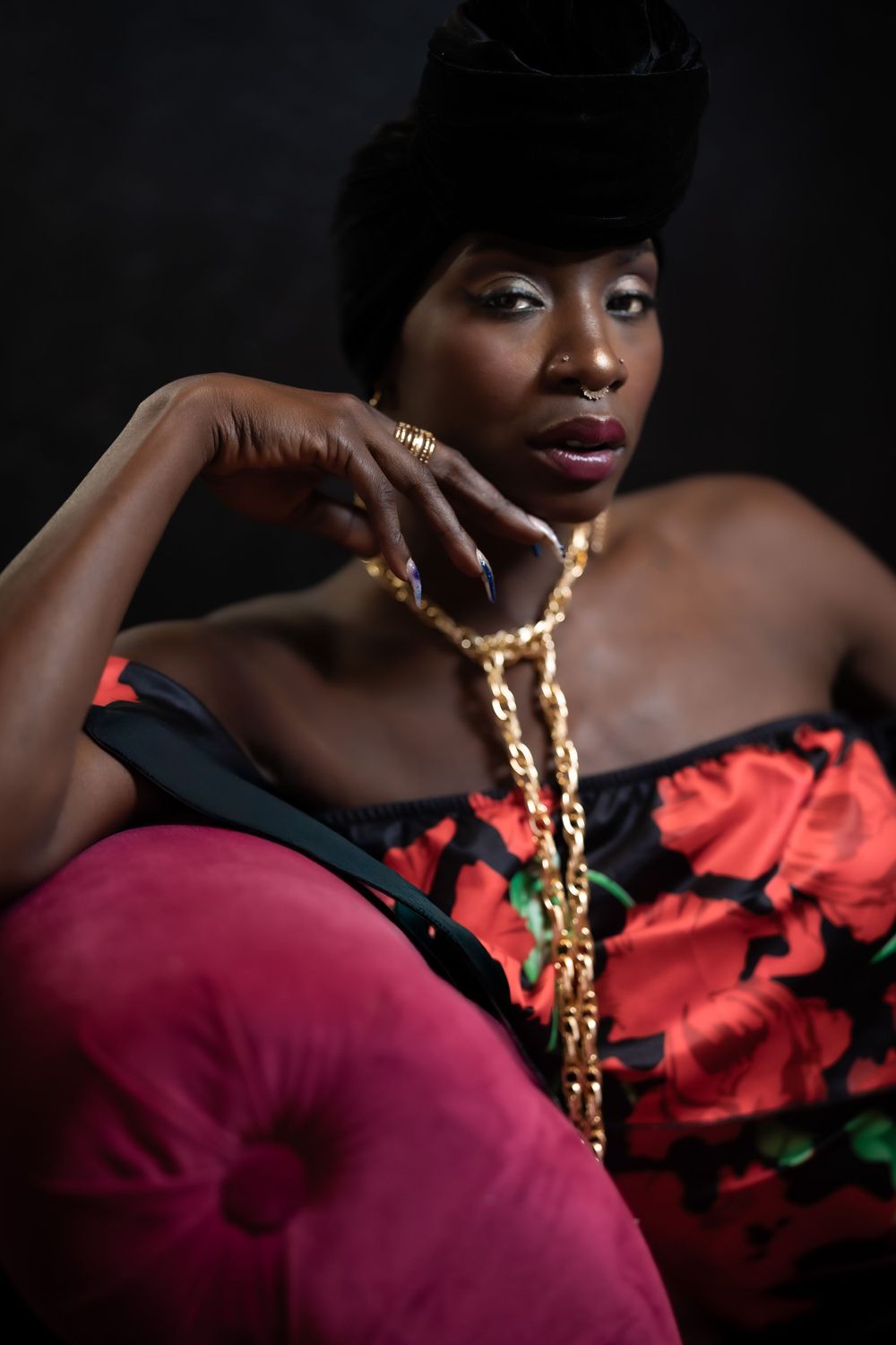 Elegant portrait of woman in floral dress and fur hat with gold chain necklace.