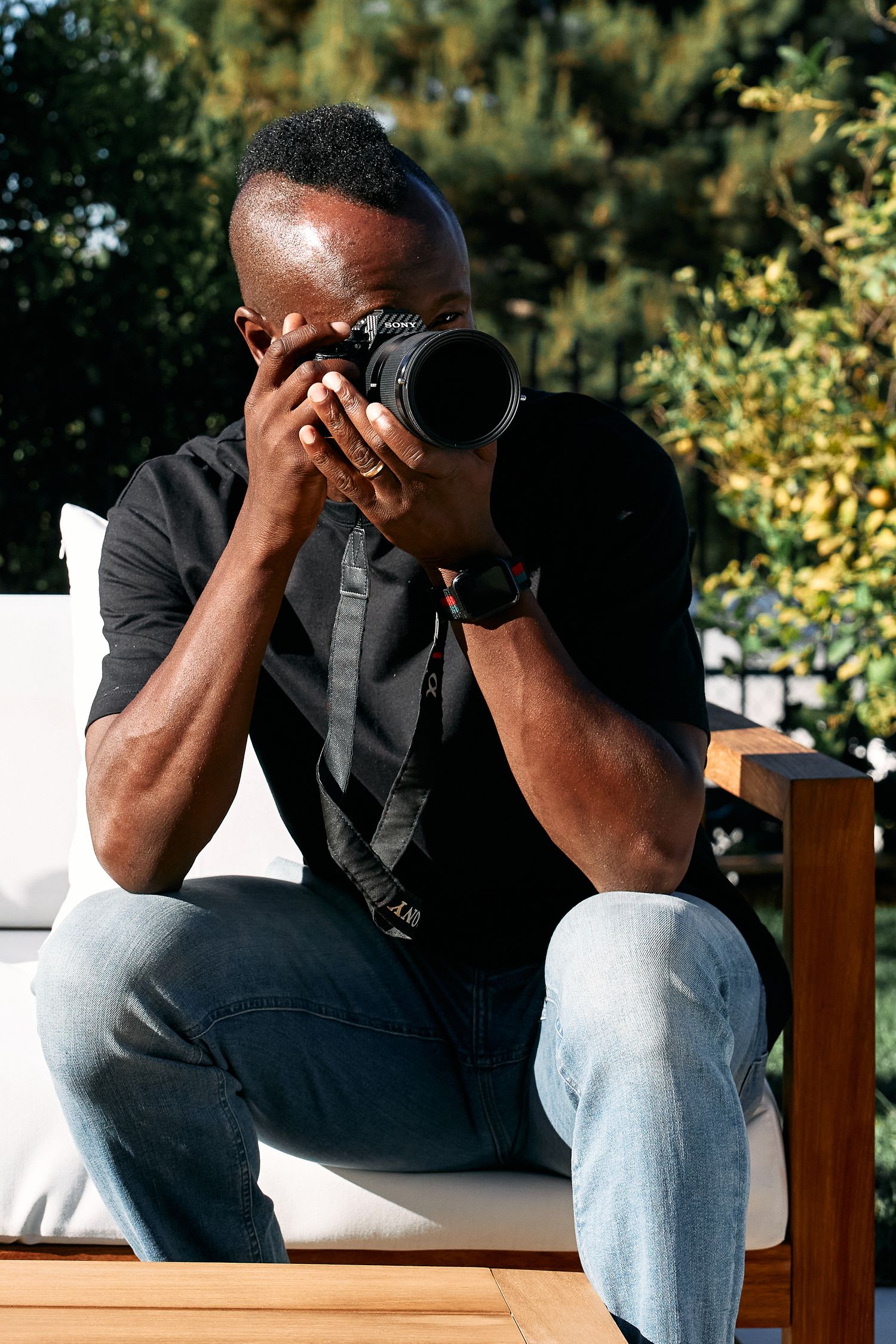 Professional photographer wearing black shirt taking photos outdoors.