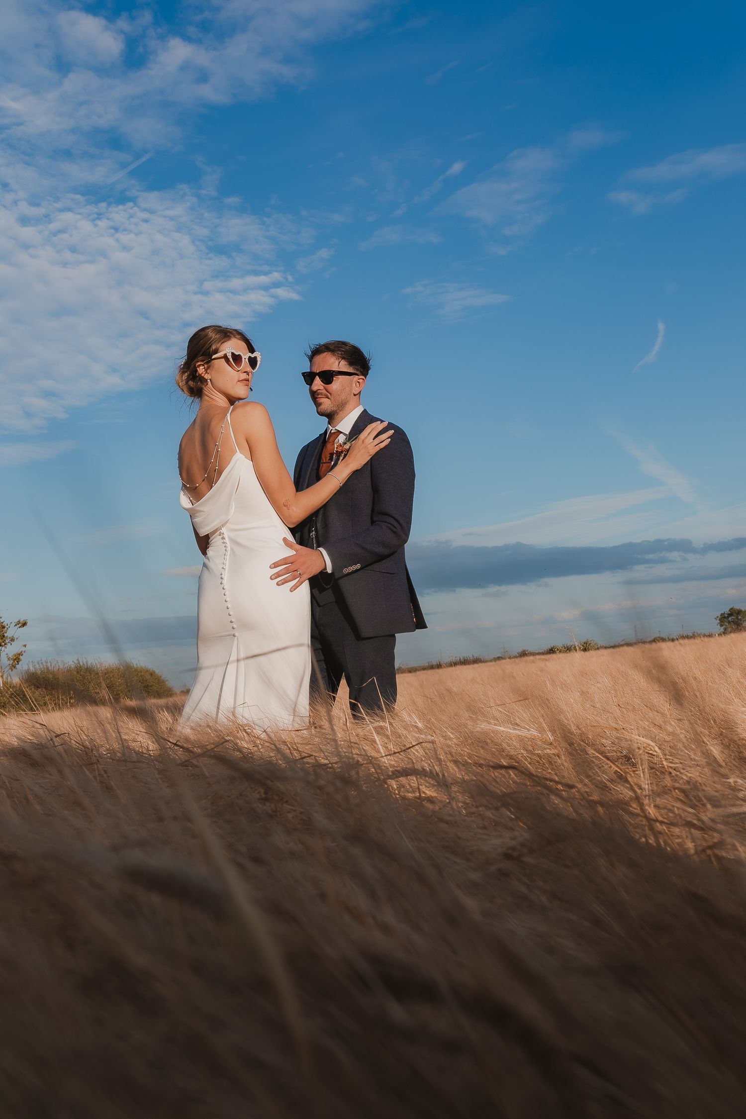 A couple shares a romantic moment in a golden wheat field under bright blue skies. Photographer. Hull. East Yorkshire. Photography