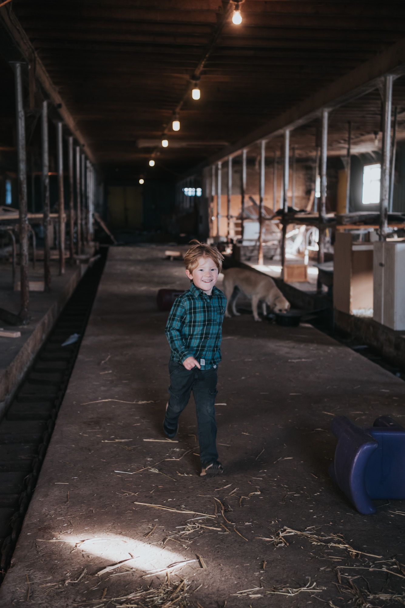 A young boy runs through a barn with a big smile on his face.