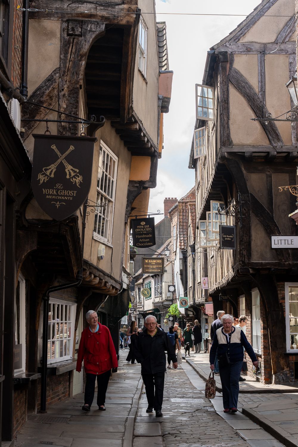 Medieval timber-framed buildings line a narrow cobblestone street with overhanging upper floors.