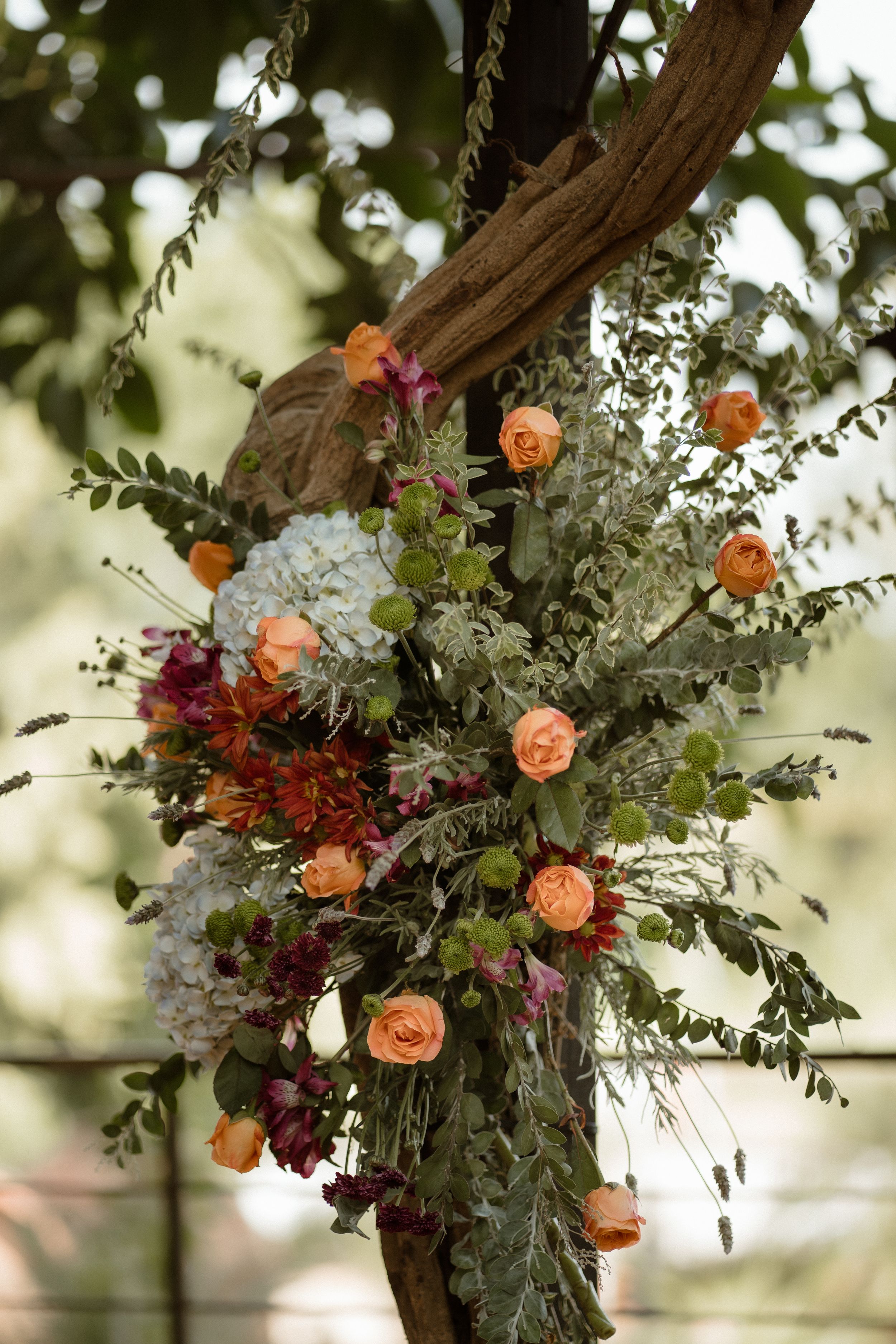 Beautiful floral arrangement with peach roses and white flowers adorning a rustic wooden arch.