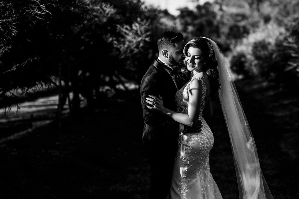 Dramatic black and white portrait of couple in wedding attire outdoors.