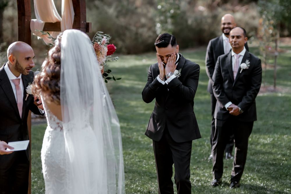 An emotional wedding ceremony moment captured outdoors with attendees in formal attire.