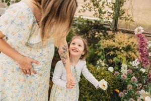 A joyful moment shared between parent and child in a blooming garden greenhouse with pink flowers and greenery.