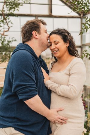 A couple expecting a baby shares intimate moments in a series of candid photos showing them embracing and laughing together.