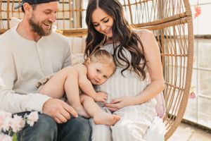 A tender family moment shared on a woven rattan chair as they lovingly embrace eachother for a maternity photo.