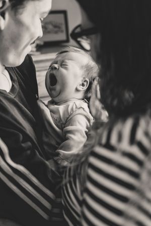 A tender black and white photo sequence shows a parent holding and a small baby in their arms while it yawns big and gets ready for sleep.