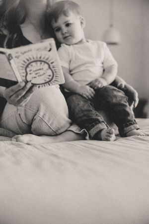 A black and white photo series shows a woman reading to her child and resting together on the bed.
