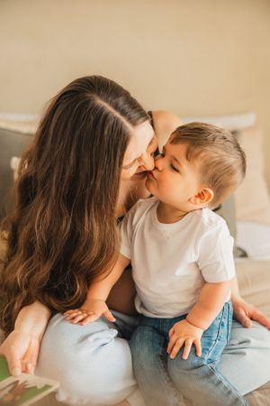 A tender moment between parent and child sitting together on a soft surface in natural lighting.