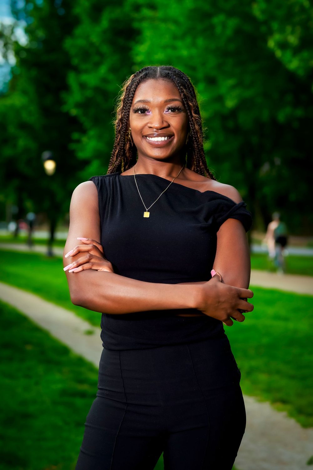 A graduation photoshoot in a park featuring poses in a black dress against lush greenery.