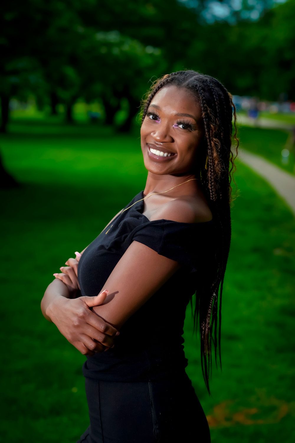 Portrait series in a park setting showing joyful poses in a black dress.