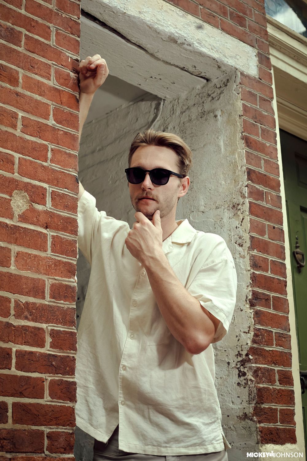 A person in white clothing strikes dynamic poses against a brick wall in a photo sequence.