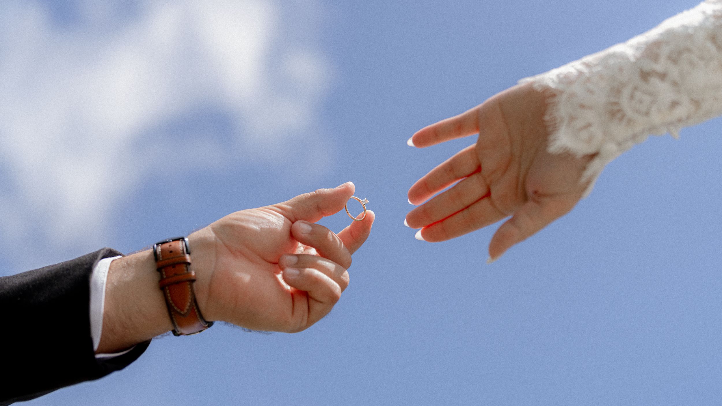 A sequence of hands performing a rock paper scissors game against a bright blue sky background.