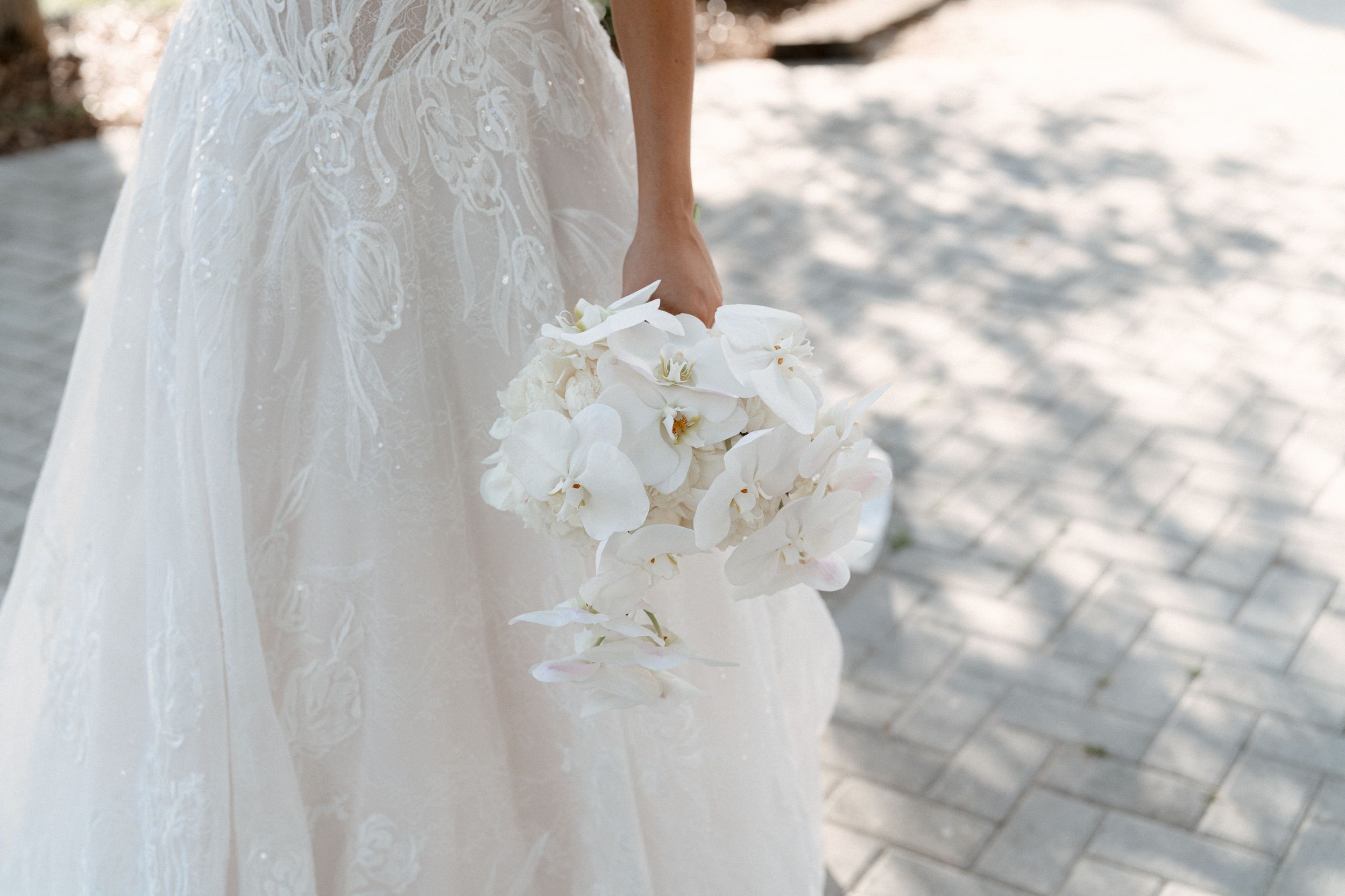 Close-up details of a white lace wedding dress with delicate floral embellishments and beading.