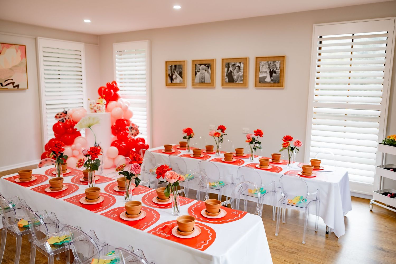 Party table setup with red and white decor featuring clear chairs and balloon arrangements.