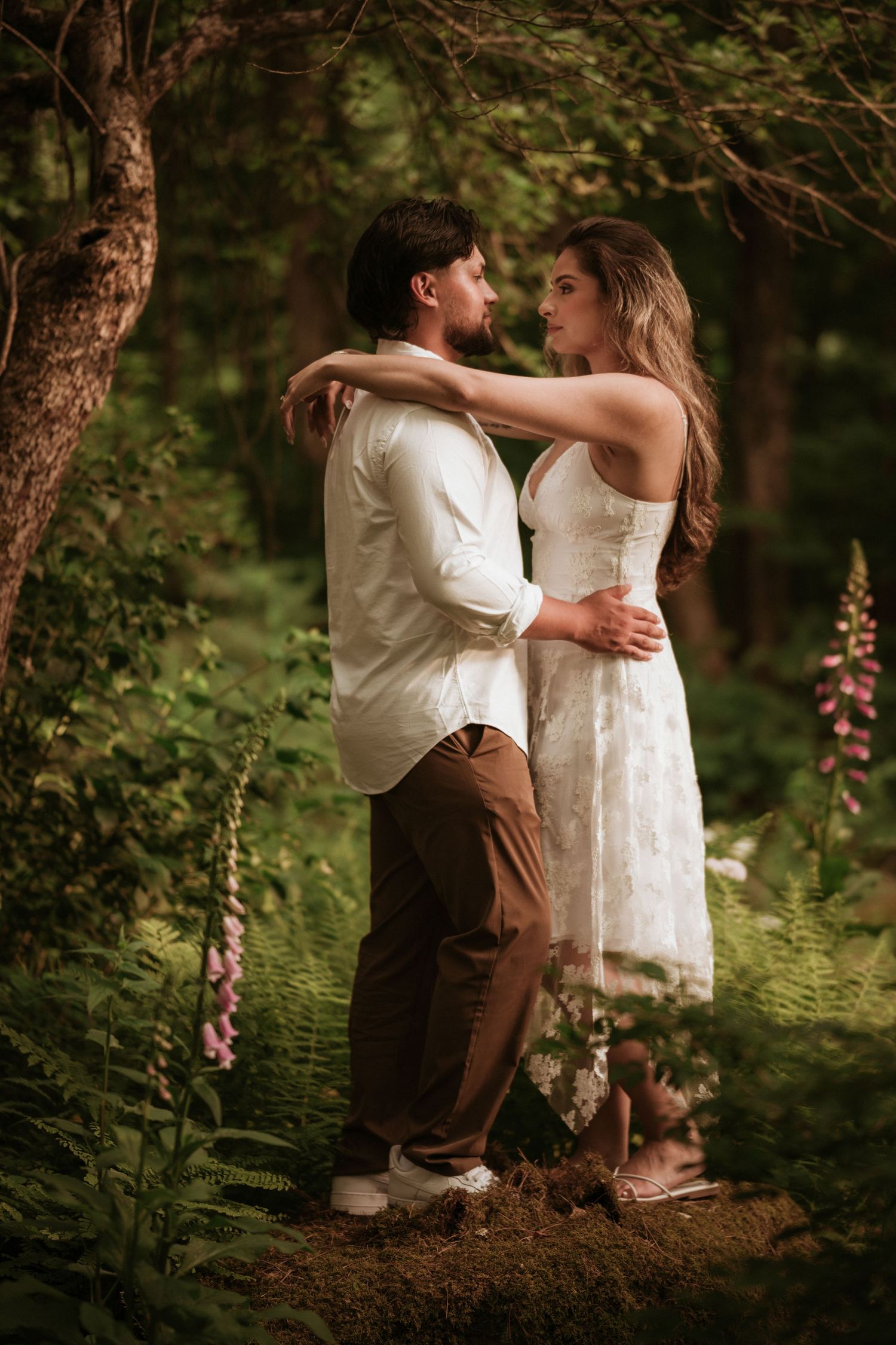 Couple wearing mountain bike helmets share a kiss while holding hands in a forest.