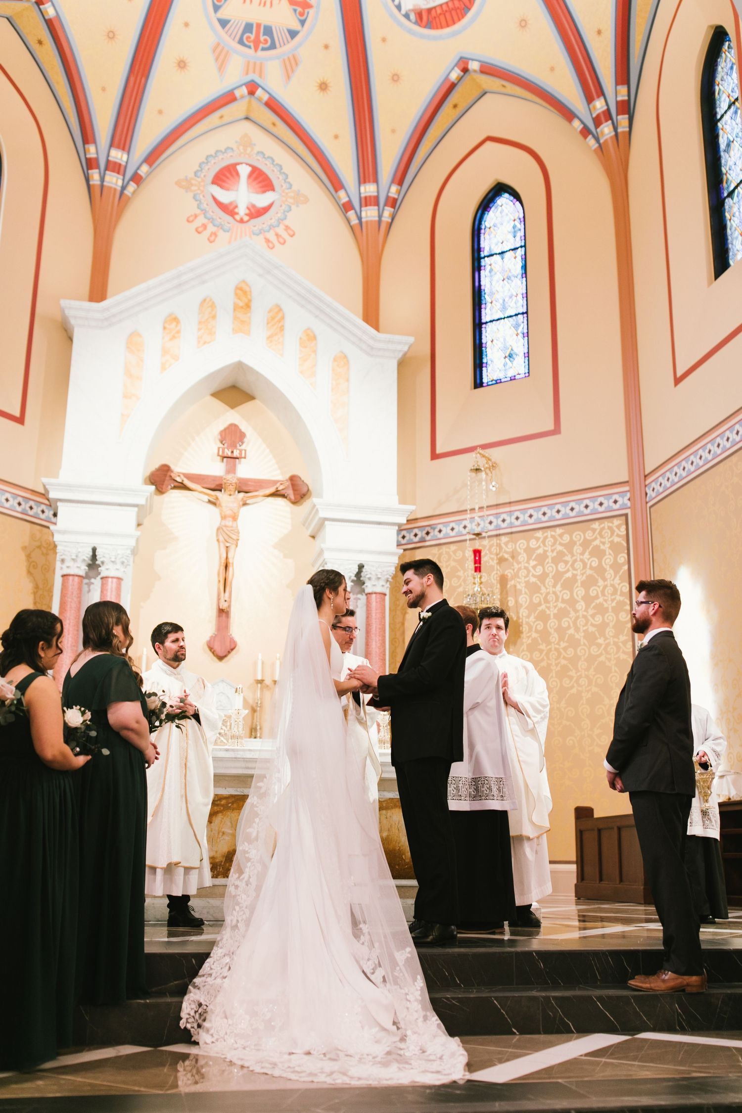 A Catholic wedding ceremony in progress inside a church with ornate orange and white architectural details.