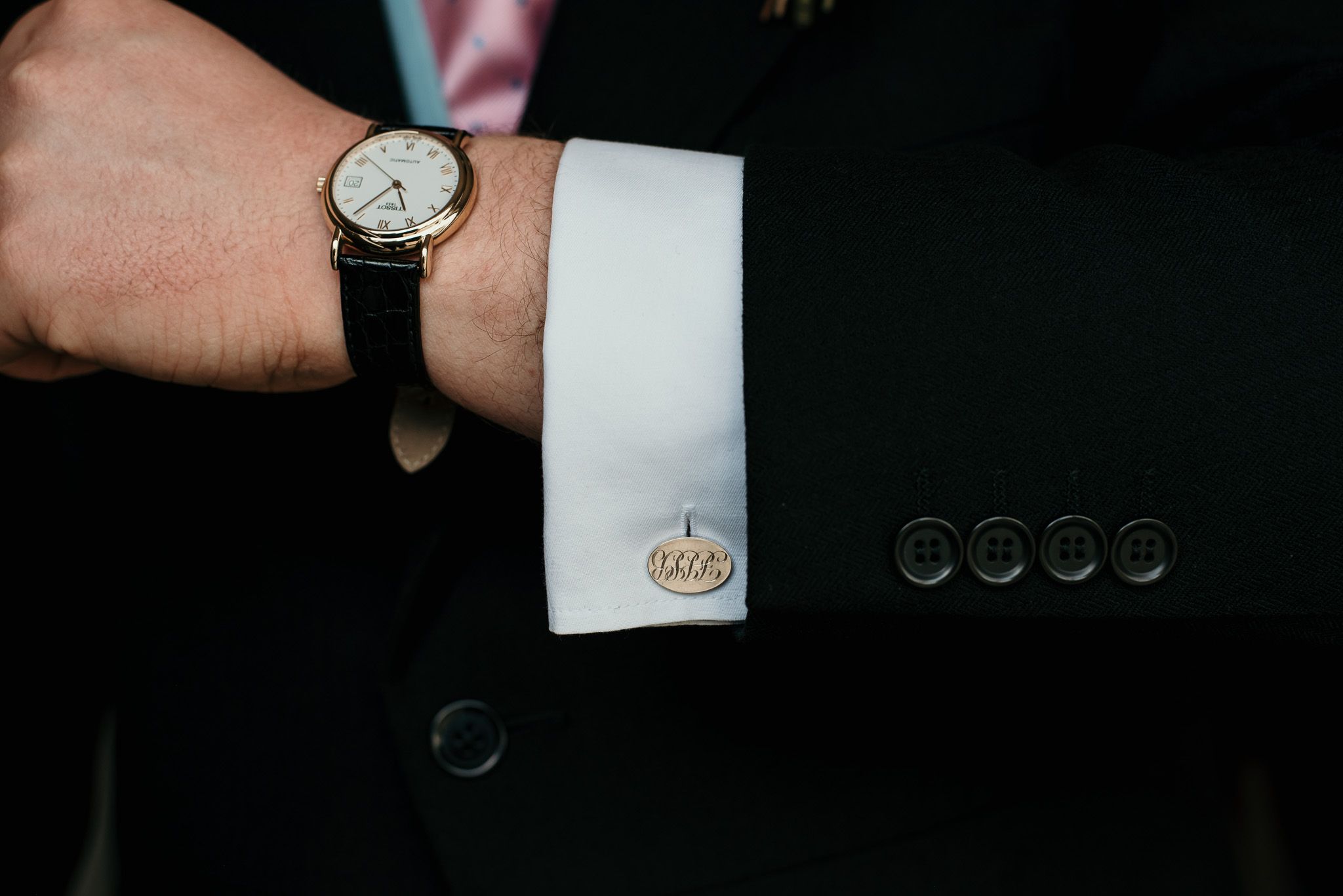 Close-up details of formal suit buttons and watch accessories.