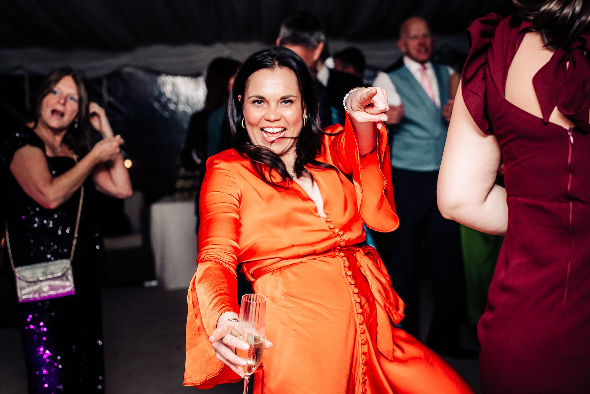 Wedding guests dancing and celebrating at a lively reception with colorful attire.