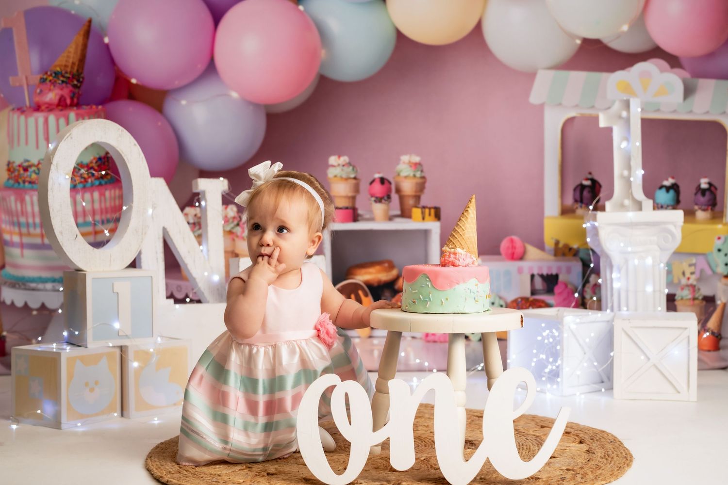 Pink and purple balloon arch with white decorative letters for birthday celebration.