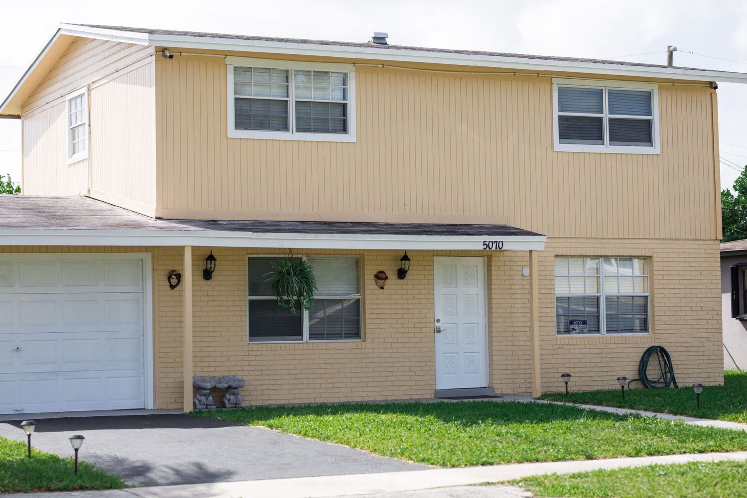 A two-story beige suburban house with attached garage and white trim.