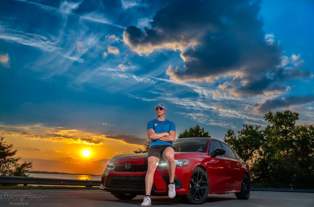 Sunset automotive photo featuring high school senior and a red sports car and dramatic sky.