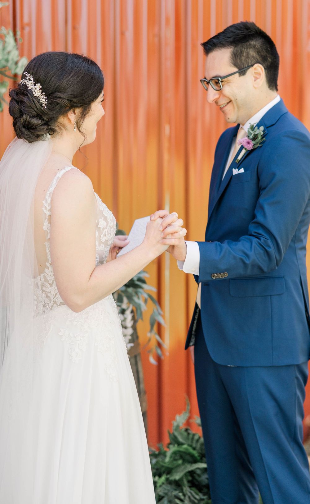 Joyful wedding ceremony moment against vibrant orange background.