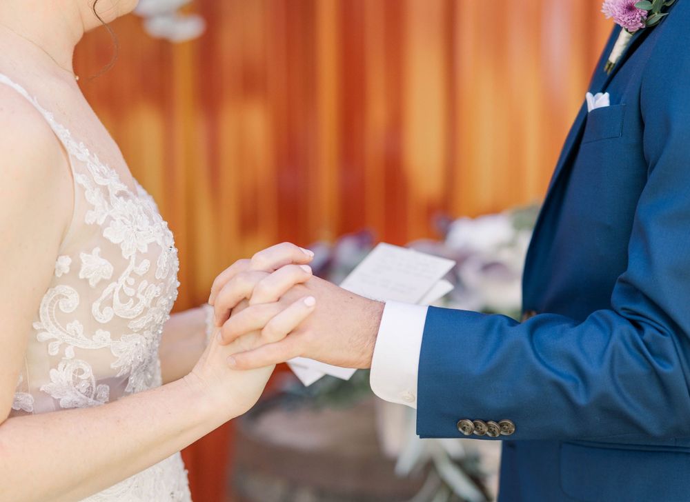 Close-up of hands exchanging rings during wedding ceremony. The 1932 Barn Venue, Charlotte, NC