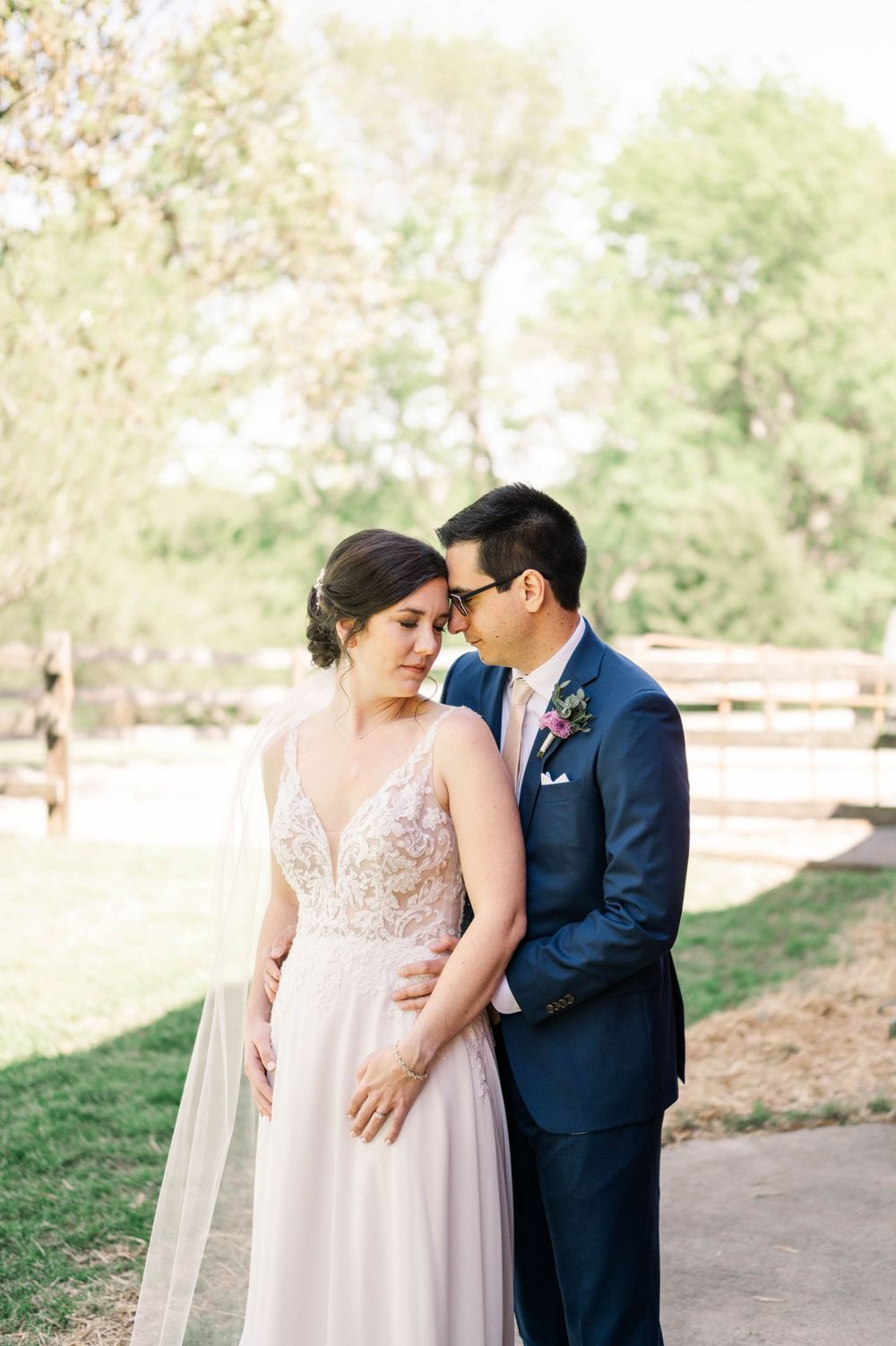 A romantic moment between newlyweds sharing an intimate pose in a sunlit outdoor setting.