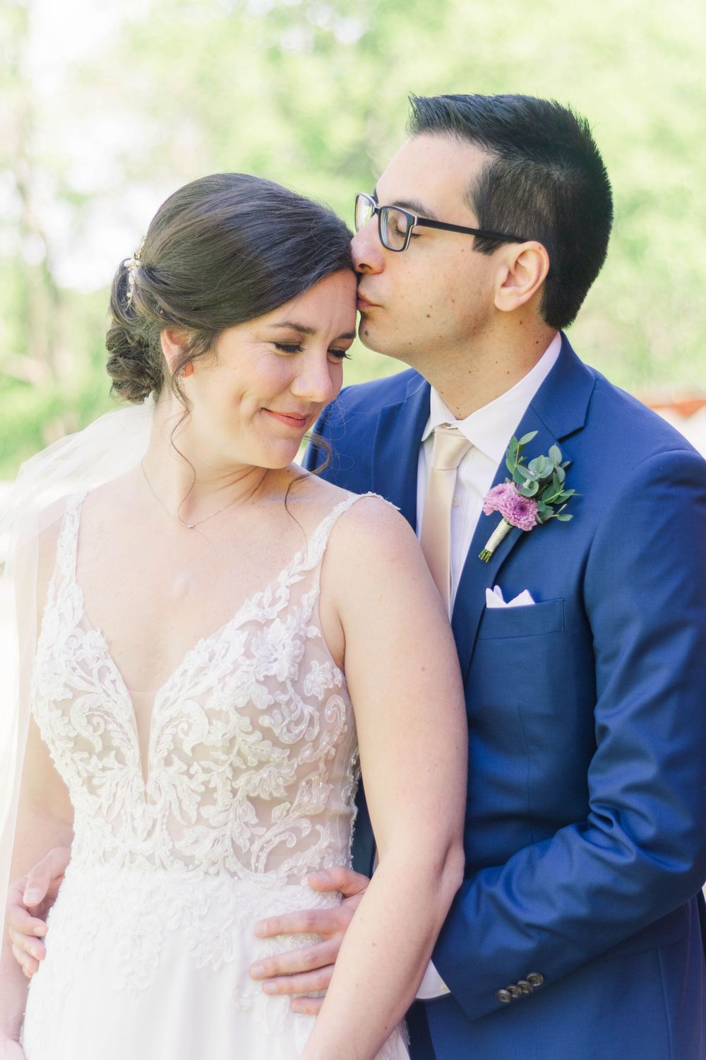 Romantic wedding portrait with bride in lace gown and groom in navy suit.