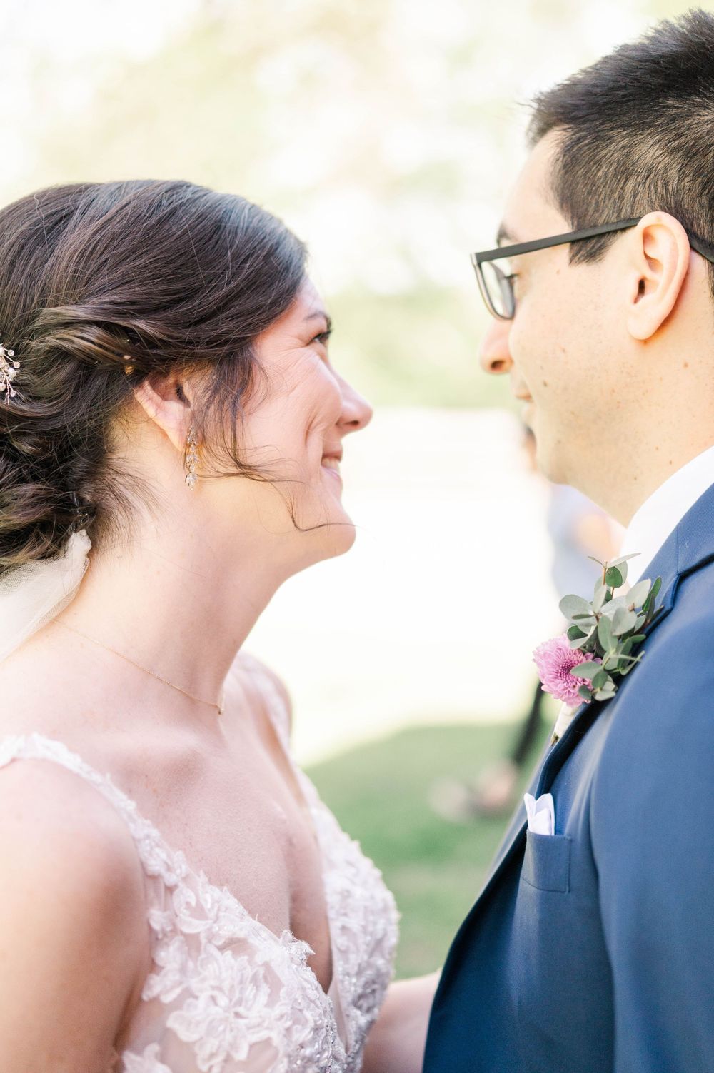 A tender moment between newlyweds sharing a joyful laugh in an outdoor wedding setting.